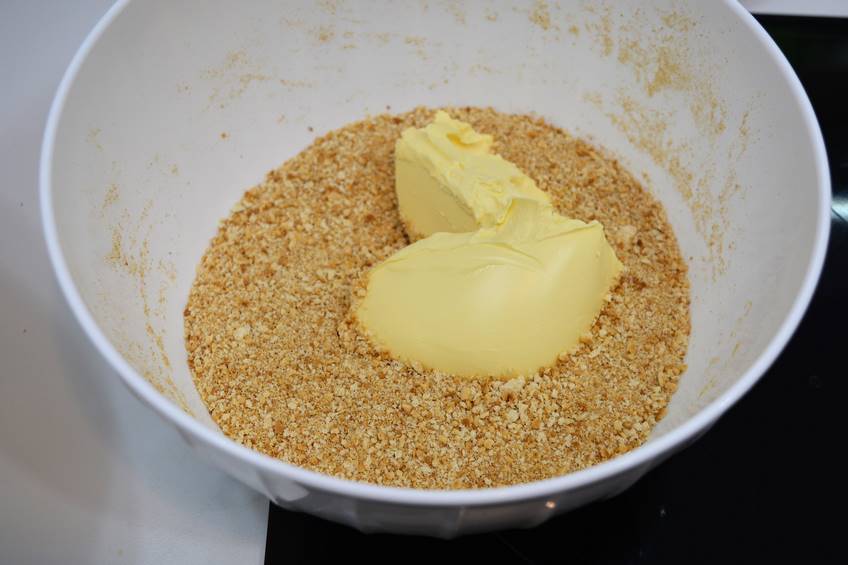 Pulverizar las galletas y mezclarlas con la mantequilla