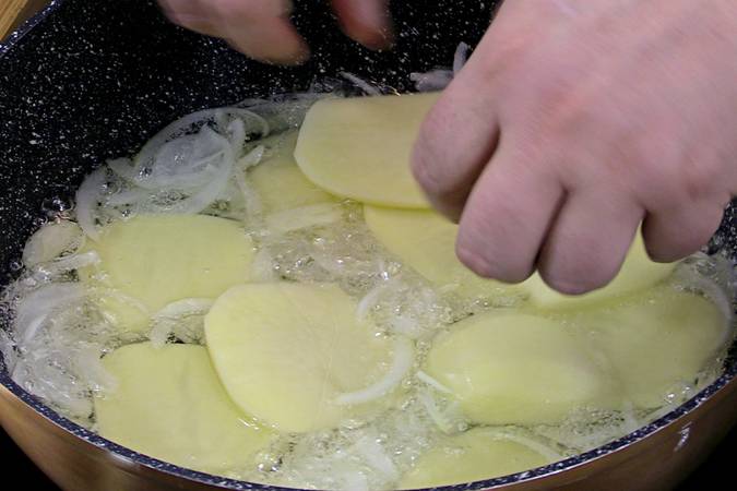 Pelar y cortar las patatas en láminas y freírlas a fuego medio